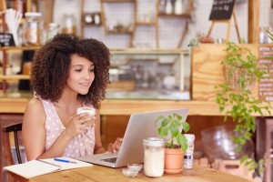 Beautiful young freelancer working on her laptop in a coffee with wifi